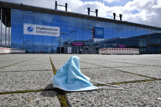 A mask lies in front of the vaccination centre in Erfurt, Germany, Tuesday, March 16, 2021. After the stopping of AstraZeneca vaccinations thousands of appointments are cancelled in Thuringia. According to the Thuringian Ministry of Health, the central vaccination centers in Gera and Erfurt are affected, where about 2800 vaccination appointments are cancelled per day. (Martin Schutt/dpa via AP)