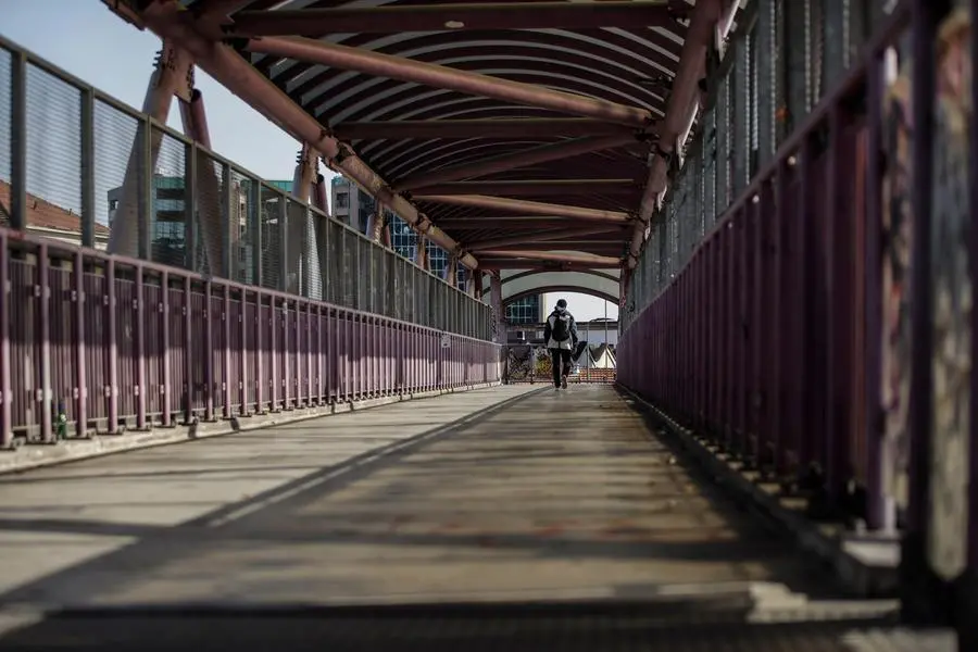 A man walk on a bridge next to the CPR (Centro di Permanenza per il Rimpatrio) in Via Corelli, in Milan, Wednesday, Sept. 30, 2020. (AP Photo/Luca Bruno)