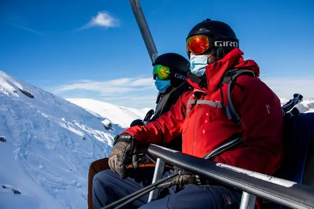 Skiers wearing face masks ride a chairlift on the opening day of the Verbier ski area in the Swiss Alps during the coronavirus disease (COVID-19) outbreak, in Verbier, Switzerland, Friday, Oct. 30, 2020. (Jean-Christophe Bott/Keystone via AP)