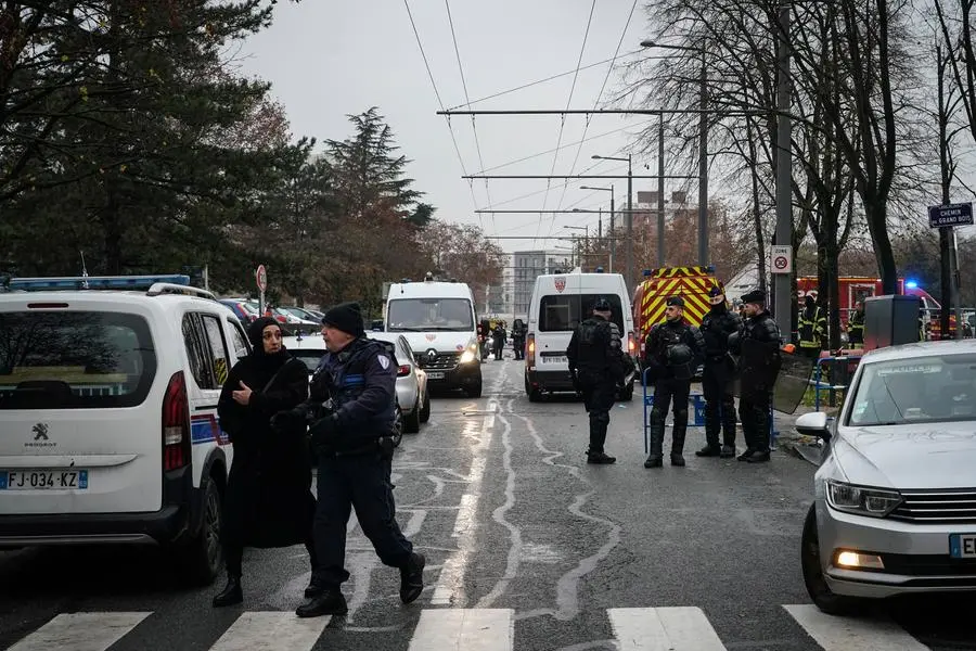 Police officers stand in a security perimeter set up next to apartment buildings, in Vaulx en Velin, outside Lyon, central France, Friday, Dec. 16, 2022. French authorities say 10 people including five children died in a fire in an apartment building outside the city of Lyon. The cause of the fire is being investigated. (AP Photo/Laurent Cipriani)