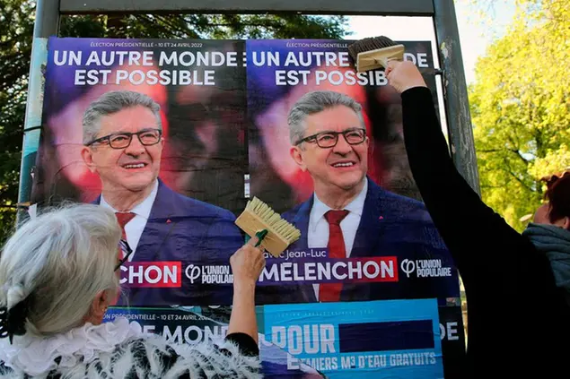 CAPTION CORRECTS THE SPELLING - Supporters of of far-left leader Jean-Luc Melenchon glue a campaign poster in Hendaye, southwestern France, Thursday, April 7, 2022. The two-round presidential election will take place on April 10 and 24, 2022. (AP Photo/Bob Edme)