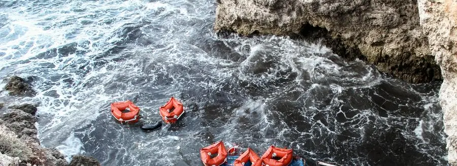Debris and life jackets from capsized boat float by the rocky shore of the Sicilian island of Lampedusa, southern Italy, Sunday, Nov. 24, 2019. Italian news reports say the Italian coast guard has recovered seven bodies of migrants near Lampedusa and kept up its search Sunday of rough seas for as many as 13 other migrants feared missing after their boat capsized on Saturday. (AP Photo/Mauro Seminara)